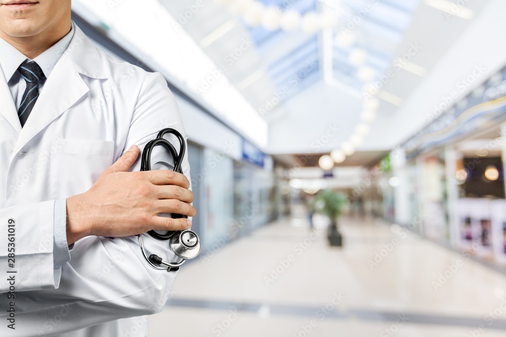 Wall mural Male doctor with stethoscope on blurred hospital background