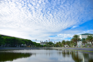 Obraz premium The pond is surrounded by trees and the factory. The background is blue sky and Cloud