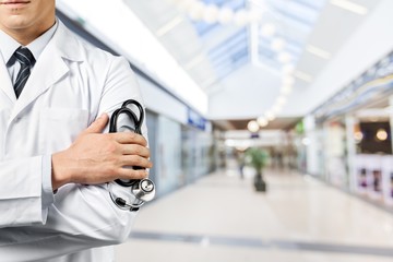 Male doctor with stethoscope on blurred hospital background