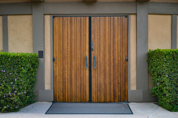 Beautiful rustic wooden door sits closed between two lush hedges