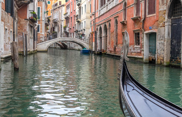 Fototapeta na wymiar The bow of a gondola, depicting no gondolier, navigating one canal at Venice