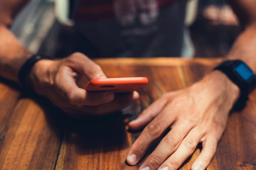 young guy with a beard in a shirt and headphones,Young and smiling man sitting on the roof with mobile phone and listening music (intentional sun glare and vintage color, focus on mobile phone