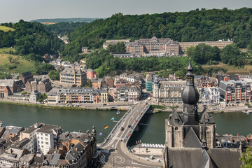Dinant, Belgium - June 26, 2019: Seen from Citadelle. Large building on top is College Notre Dame de Bellevue, school system from primary to high school. Forests in back. City, river and church - obrazy, fototapety, plakaty