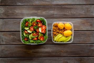 food container with salad on wooden background top view