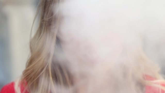 Stylish girl in a city. Lady use the electronic cigarette