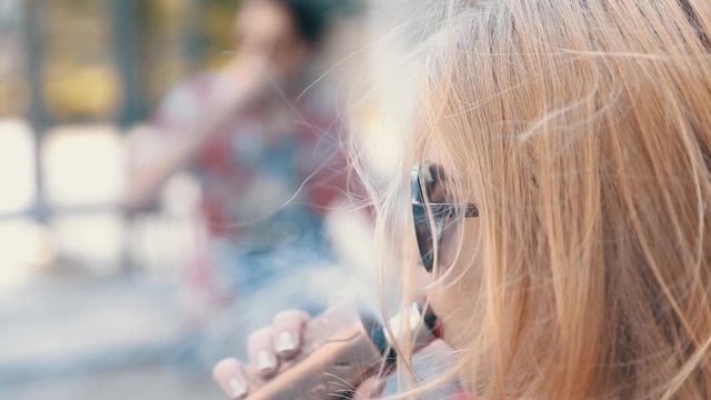 Stylish couple in a city. Two people use the electronic cigarette