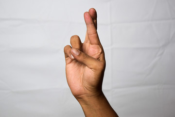 Close up Asian man shows hand gestures it means Fingers Crossed isolated on white background