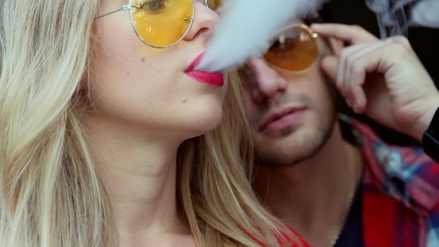 Stylish couple in a city. Two people use the electronic cigarette