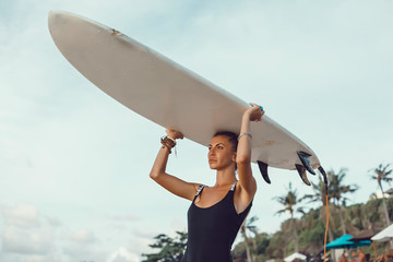 Surfer girl walking with board on the sandy beach. Surfer female.Beautiful young woman at the...