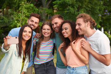 Happy young people taking selfie in park
