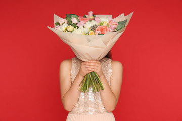 Young woman holding beautiful flower bouquet on red background