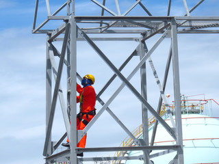 Man Working on the Working at height. Professional industrial climber in helmet and uniform works at height. Risky extreme job. Industrial climbing at construction site.   