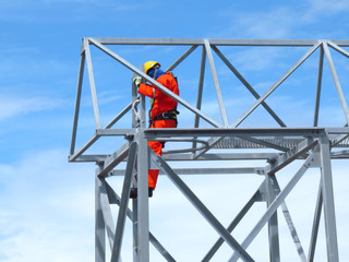 Man Working on the Working at height. Professional industrial climber in helmet and uniform works at height. Risky extreme job. Industrial climbing at construction site.   