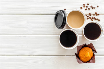 paper cups with black coffee and cappuccino to take away, beans, muffin on white wooden background top view mockup
