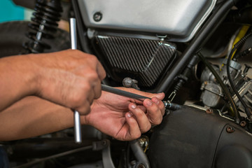 Image is Close up,People are repairing a motorcycle Use a wrench and a screwdriver to work.