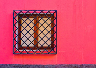 Barred closed window in vibrant pink wall, concept of love as a prison.