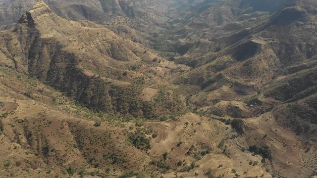 Revealing drone shot tilting from dry rural fields to mountain ranges of Simien national park in Ethiopia