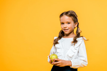 happy child holding tasty apple and smiling isolated on orange