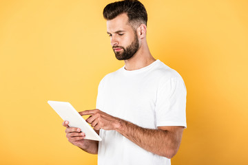 handsome man in white t-shirt using digital tablet isolated on yellow