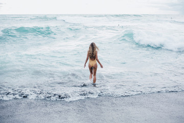 Beautiful young woman posing on the beach with a yellow tissue. Happy smiling girl with scarf enjoying at beach. Freedom and carefree concept,Bali, happy face, smile,sport,withe color,waves,tanning
