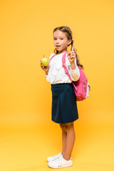 adorable schoolkid holding apple and pointing with finger on orange