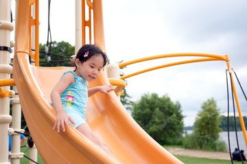 Active little Asian girl playing on the public playground