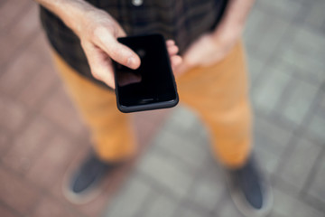 young handsome bearded hipster man using smartphone and listening music with earphones in the city, headphones, sunglasses street, outdoor portrait, cap, hat, concept, hipster male, wall