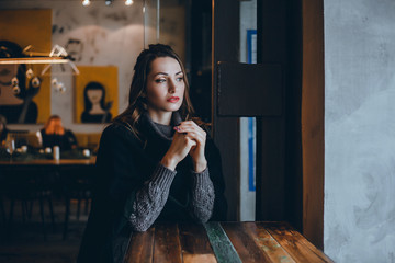 A beautiful girl in a beige jacket drinks coffee from a glass talking on the phone, wearing sunglasses works in the office in the business center, the manager, the employee of the company, happy face