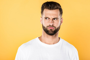 Obraz premium worried handsome man in white t-shirt looking away isolated on yellow