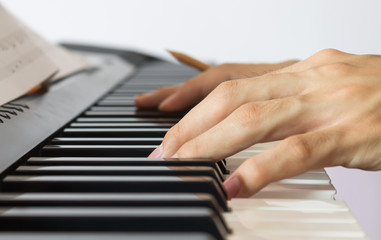 Fototapeta na wymiar Piano Player Hand on Electric Piano with Sheet music