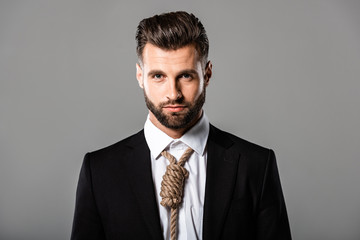 depressed handsome businessman in black suit with noose on neck isolated on grey