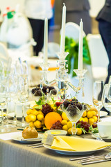 Party dinner table setting with tableware and silverware and glasses set and Candlestick and flower in restaurant.