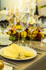 Party dinner table setting with tableware and silverware and glasses set and Candlestick and flower in restaurant.