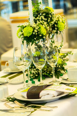 Party dinner table setting with tableware and silverware and glasses set and Candlestick and flower in restaurant.