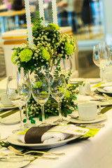 Party dinner table setting with tableware and silverware and glasses set and Candlestick and flower in restaurant.