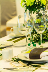 Party dinner table setting with tableware and silverware and glasses set and Candlestick and flower in restaurant.