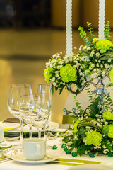 Party dinner table setting with tableware and silverware and glasses set and Candlestick and flower in restaurant.