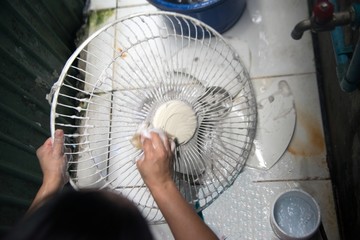 Housewife use white cloth Wipe and clean the electric fan.