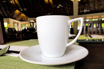 white cup stands on a table in a restaurant. Breakfast concept.