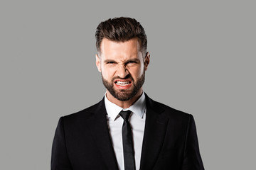 angry bearded businessman in black suit isolated on grey