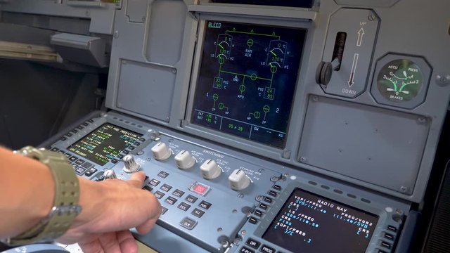 Pilot hand pushing buttons for checking the aircraft status