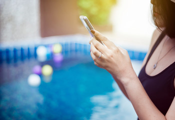 Beautiful asian woman using mobile phone at swimming pool,Happy and smiling,Relax time,Summer travel concept