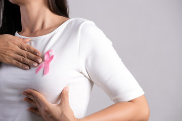 Closeup of pink badge ribbon on woman chest to support breast cancer cause. Healthcare, medicine...