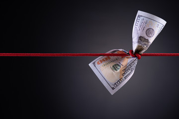 American dollar tied up in red rope knot on dark background with copy space. business finances,...
