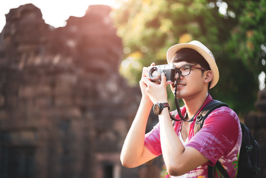 Young Man Photographer Traveler with backpack taking photo with his camera, Great wall in background at historical place. Lifestyle and travel concept.