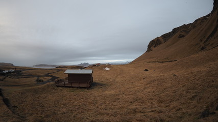 Small house sits on a valley next to the mountains in Iceland