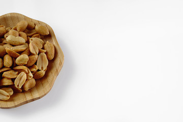 wood plate of salted peanuts isolated on white background. snack to beer