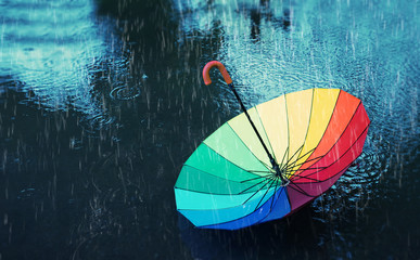 abstract autumn background. colorful umbrella in rain. multicolored umbrella in puddle, rainy weather. fall time. shallow depth, soft selective focus
