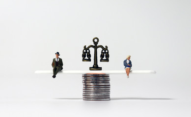 Miniature people and piles of coins. The concept of economic equality between men and women.