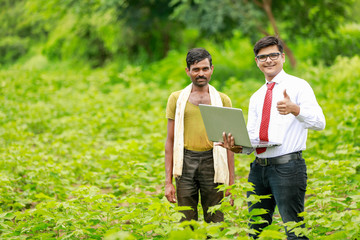 Indian farmer with agronomist at Green Corn Field, showing Thumps up After some information in laptop